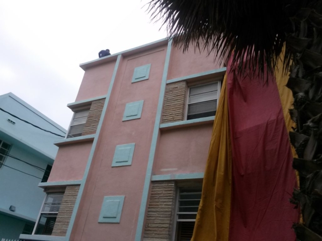 Workers applying fumigation tent on top of a pink apartment building