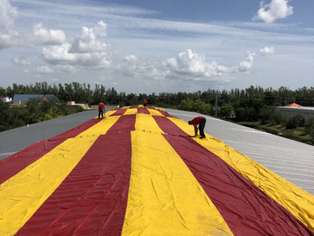 Workers applying fumigation tent over a building