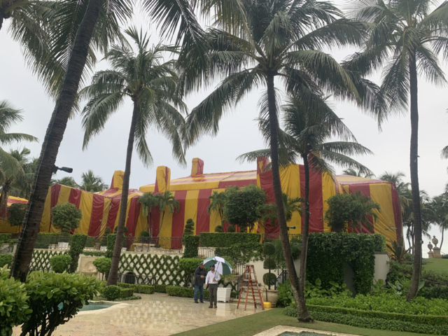 Two men standing in the rain with a red and yellow tent for fumigation